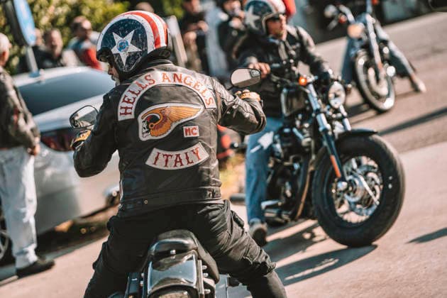 Milan, italy 20 september 2025: hells angels rider on classic cruiser in leather jacket with patches and american flag helmet, embodying biker culture and freedom Hells angels motorcycle club members riding bikes in italy Copyright: xx road 165