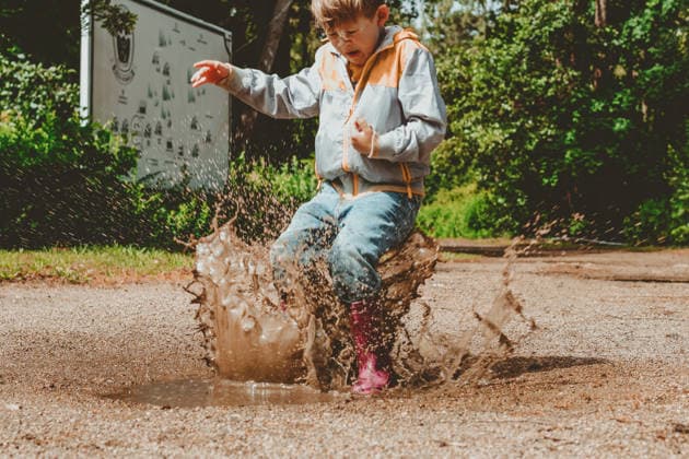 Ein fröhliches Kind springt in wasserdichten Stiefeln durch eine Pfütze. Ein Junge, der voller Spritzwasser ist, spielt in einem herbstlichen Park. A happy child jumps in a puddle in waterproof boots. A boy with splashes is playing in an autumn park. Outdoor activities in rainy weather (License=RF) ,model released, Symbolfoto Copyright: xZoonar.com ElenaxEsichx 24940207 ,model released, Symbolfoto ,property released