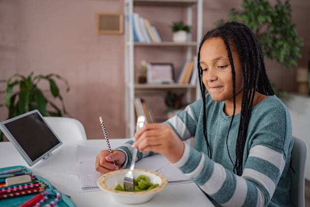 Eine junge Schülerin isst beim Lernen einen gesunden Kiwi-Snack Young girl doing homework at desk while enjoying an healthy kiwi fruit snack (License=RF) ,model released, Symbolfoto Copyright: xZoonar.com JelenaxCvetkovicx 24952096 ,model released, Symbolfoto ,property released