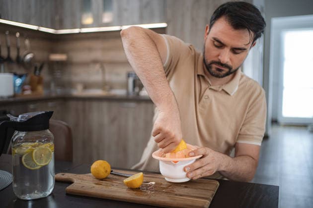 Ein Mann, der in der Küche Zitronen auspresst, um Entgiftungswasser oder Limonade zuzubereiten Mid adult man squeezing lemons in the kitchen preparing detox water or lemonade (License=RF) ,model released, Symbolfoto Copyright: xZoonar.com JelenaxCvetkovicx 24952273 ,model released, Symbolfoto ,property released