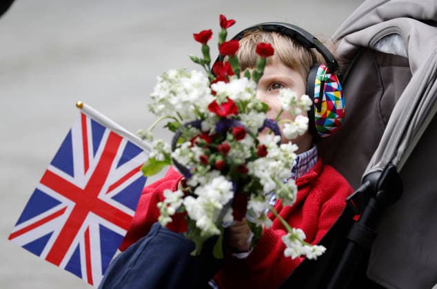 A youngster holding a Union Jack flag and a bouquet of flowers waits for the arrival of King Charles III and Queen Camilla as they visit the 9 11 Memorial pools in New York City on Wednesday, April 29, 2026. King Charles III and Queen Camilla will visit the nation s capital, New York City, and Virginia during the trip arranged to celebrate the United States of America s 250th anniversary of its independence.  NYP20260429804 JOHNxANGELILLO