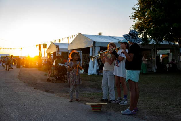 Young girls play the trumpet for tips as people depart the New Orleans Jazz and Heritage Festival at the Fairgrounds Race Courts and Slots in New Orleans, Louisiana on Sunday, May 3, 2026. Organizers expected about 400,000 to attend, but the finally tally, which won t be available for a few days, may be impacted by rain that interrupted festival operations Thursday and Friday.  NOL20260503320 BONNIExCASH