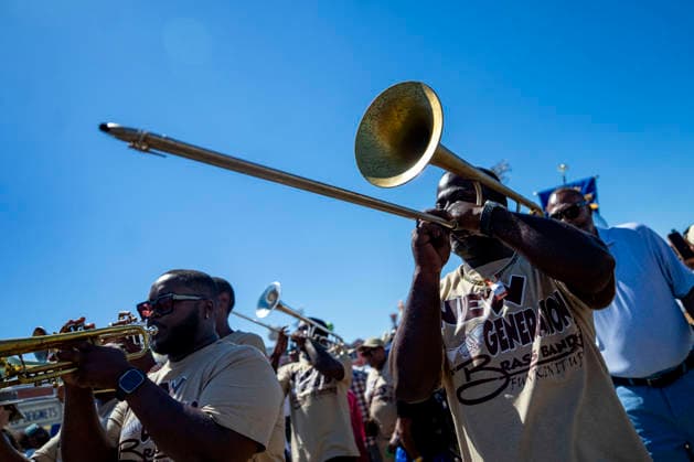 A brass band walks with members of the Zulu Social Aid and Pleasure Club walking group parade through the New Orleans Jazz and Heritage Festival at the Fairgrounds Race Courts and Slots in New Orleans, Louisiana on Sunday, May 3, 2026. Organizers expected about 400,000 to attend, but the finally tally, which won t be available for a few days, may be impacted by rain that interrupted festival operations Thursday and Friday.  NOL20260503314 BONNIExCASH