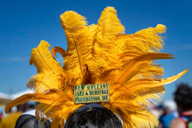 A woman with a feather headpiece walks through the New Orleans Jazz and Heritage Festival at the Fairgrounds Race Courts and Slots in New Orleans, Louisiana on Sunday, May 3, 2026. Organizers expected about 400,000 to attend, but the finally tally, which won t be available for a few days, may be impacted by rain that interrupted festival operations Thursday and Friday.  NOL20260503315 BONNIExCASH
