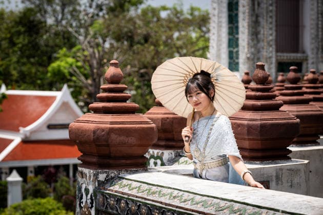 Daily Life In Bangkok A tourist wearing a traditional Thai costume has their photo taken at Wat Arun in Bangkok, Thailand, on May 6, 2026. The Thai government, led by Prime Minister Anutin Charnvirakul, has approved an emergency decree to borrow 400 billion Thai Baht (12.4 million USD) for a stimulus plan aimed at alleviating rising cost-of-living pressures and supporting measures to reduce energy costs amid the conflict involving the United States, Israel, and Iran, which began in late February 2026. Bangkok Thailand Thailand  Copyright: xMattxHuntx originalFilename: hunt-dailylif260506_npQVt.jpg