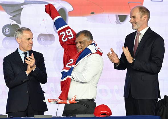 May 6, 2026, Mirabel, Pq, Canada: Prime Minister Mark Carney, left, and Lars Wagner, CEO, Airbus Commercial Aircraft, right, look on as AirAsia CEO Tony Fernandes puts on a Montreal Canadiens hockey jersey during an event at the Airbus A220 Delivery Center in Mirabel, Que., Wednesday, May 6, 2026, where AirAsia placed a landmark order for 150 Airbus A220 aircraft. Mirabel Canada - ZUMAc35_ 20260506_zaf_c35_172 Copyright: xGrahamxHughesx