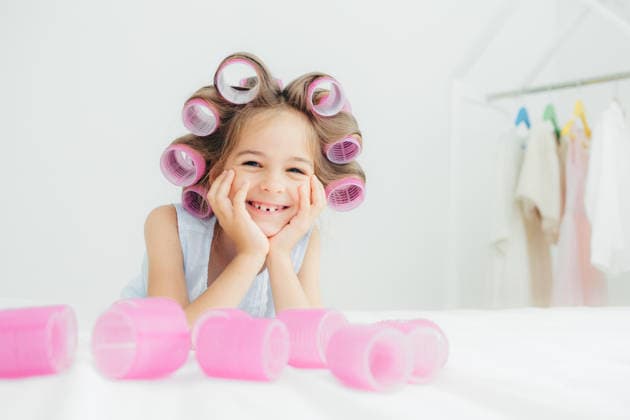 Ein fröhliches kleines Mädchen mit rosa Lockenwicklern lächelt auf dem Bett in einem strahlend weißen Schlafzimmer, während es zu Hause eine verspielte Schönheitspflege-Routine durchführt Happy Little Girl Wearing Pink Hair Rollers Smiling on Bed in Bright White Bedroom During Playful Beauty Routine at Home (License=RF) ,model released, Symbolfoto Copyright: xZoonar.com ViorelxKurnosovx 25041959 ,model released, Symbolfoto ,property released