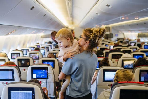 Mom calming upset child during family flight while traveling on airplane. Mother calming upset child during family flight while traveling on airplane. model released