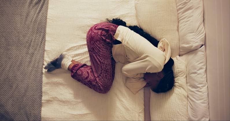 Woman, sad and stomach pain in bed with PMS, cramps and crying in high angle at home. Person or girl with stress, frustrated or agony and lying with pillow for endometriosis, uterus and health risk. (License=RF) ,model released, Symbolfoto  Copyright: xZoonar.com KasperxRavlox 21793018 ,model released, Symbolfoto ,property released