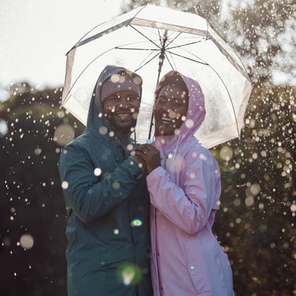 Portrait, smile and black couple with umbrella outdoor for laugh or bonding together in winter by water drop. Raincoat, happy man and woman in nature for love, protection or holding hands for support. (License=RF) ,model released, Symbolfoto  Copyright: xZoonar.com YurixArcursxpeopleimages.comx 21828595 ,model released, Symbolfoto ,property released