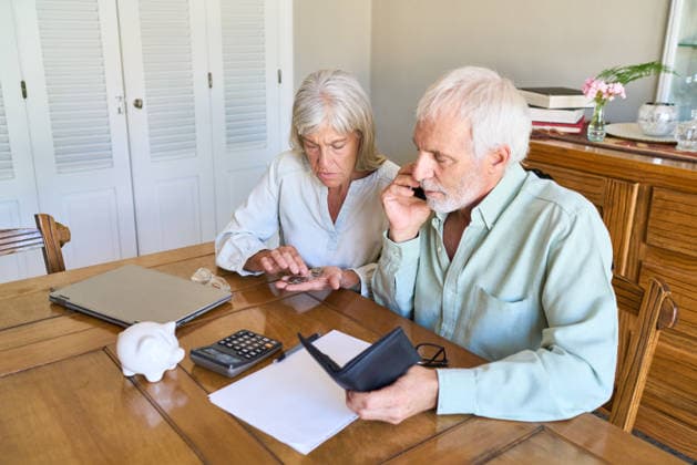 Retirement planning and financial protection. A senior couple is at home, with the woman counting coins and the man on the phone, managing their budget and discussing future financial security. (License=RF) ,model released, Symbolfoto  Copyright: xZoonar.com RobertxKneschkex 25011544 ,model released, Symbolfoto ,property released