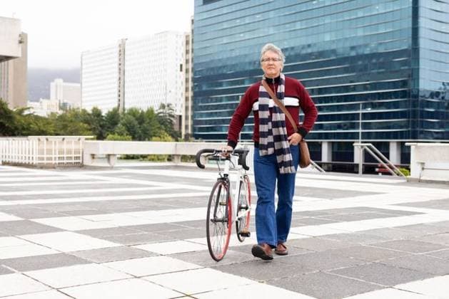 Senior man walking across checkerboard terrace with road bicycle, red rim and tan bag, copy space, model released, 07.08.2025 06:00:00, 11453086 Copyright: xIMS-260228xcreatorid:x384x 11453086