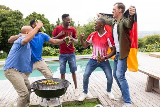 Diverse male friends cheering, grilling vegetables on charcoal grill by pool, holding beer bottles, model released, property released, Cape Town, South Africa, 18.03.2026 06:00:00, 12882310 Copyright: xIS-260416xcreatorid:x393x 12882310