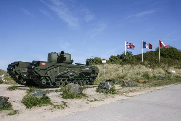 15.09.2024, Courseulles-sur-Mer-Juno Beach, Frankreich - Juno Beach ist ein Strandabschnitt in der Naehe von Courseulles-sur-Mer, wo die Allierten Streitkraefte am 6. Juni 1944 an Land gingen, um Europa von der Nazi-Herrschaft zu befreien. Juno Beach war einer der fuenf Hauptlandungsabschnitte der Alliierten in der Normandie am D-Day (6. Juni 1944). Er liegt in Frankreich zwischen Bernieres-sur-Mer und Courseulles-sur-Mer und war der Hauptsektor für die kanadischen Truppen, die unter schweren Verlusten landeten. Foto: Ein Panzer am Strand von Juno Beach, im Hintergrund die britische, die franzoesische und die kanadische Flagge. *** 15 09 2024, Courseulles sur Mer Juno Beach, France Juno Beach is a stretch of beach near Courseulles sur Mer