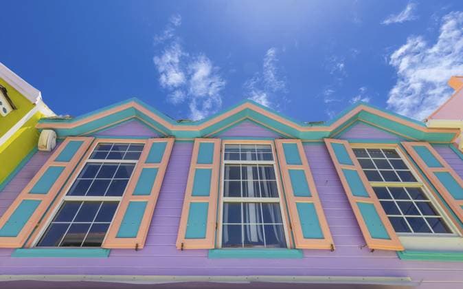 Niedrigansicht eines lebendigen lila und türkisfarbenen Kolonialgebäudes mit dekorativer Zickzack Dachlinie und blaugrünen Fensterrahmen in Philipsburg, Sint Maarten, vor einem strahlend blauen Himmel Low angle view of a vibrant purple and turquoise colonial building with decorative zigzag roofline and teal window frames in Philipsburg, Sint Maarten, against a bright blue sky Copyright: imageBROKER elov ibxelo17678656.jpg