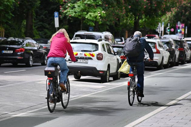 Radfahrer fahren auf einem breiten Radweg,Radschnellweg in Muenchen im Stadtverkehr, Rad fahren ,parkende Autos,PKW,parken. *** Cyclists ride on a wide cycle path, fast cycle path in Munich in city traffic, cycling, parked cars, cars, parking