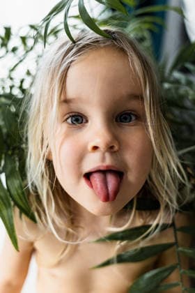 Funny toddler girl sticking tongue out among tropical houseplants Antalya, Antalya, Türkiye R_BMEE260516B-2015668-01 ,model released, Symbolfoto
