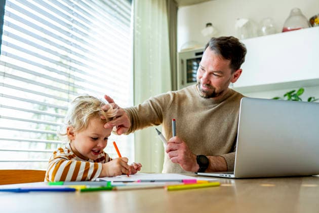 Remote working dad taking care of ill child during home office day. Father working from home while caring for sick toddler staying home from daycare. model released