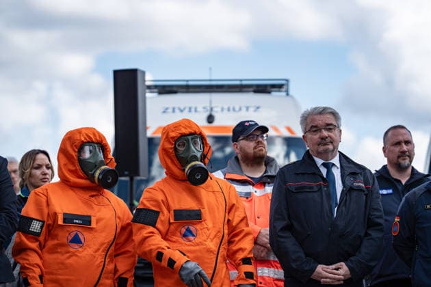 Person mit Schutzanzug und Atemschutzmaske vor einem Fahrzeug dfes Ziviklschutzes;Vorstellung Pakt für den Bevölkerungsschutz durch Bundesinnenminister und Verteidigungsminister mit Übergabe von 13 Einsatzfahrzeugen an den Zivilschutz, Berlin Berlin Deutschland Hauptbahnhof, Washingtonplatz *** Person with protective suit and breathing mask in front of a civil defense vehicle Presentation of the Civil Protection Pact by the Federal Minister of the Interior and the Minister of Defense with handover of 13 emergency vehicles to the civil defense, Berlin Berlin Germany Central Station, Washingtonplatz
