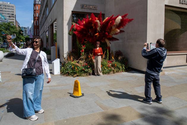 May 22, 2026, London, United Kingdom: Members of the public pose for photographs in-front of floral displays during the RHS Chelsea Flower Show. After several days of unsettled weather, large crowds gathered along Sloane Street and the surrounding areas on the penultimate day of the 2026 RHS Chelsea Flower Show to view the elaborate floral displays created for the annual event. Visitors lined the streets of Chelsea as retailers, hotels and restaurants unveiled large-scale made from fresh flowers and plants, continuing a tradition that has become closely associated with the world-famous horticultural show. London United Kingdom - ZUMAs197 20260522_aaa_s197_008 Copyright: xJamesxWilloughbyx