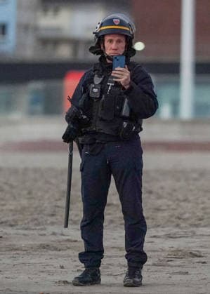 May 23, 2026, Dunkirk, Nord, France: Dunkirk, France. A police officer filming on a mobile phone as migrants attempts to board an inflatable boat at the beach at Dunkirk, to cross the English Channel. More than 200,000 migrants have crossed the Channel in small boats since 2018. Dunkirk France  - ZUMAl94_ 20260523_zaf_l94_034 Copyright: xIoannisxAlexopoulosx
