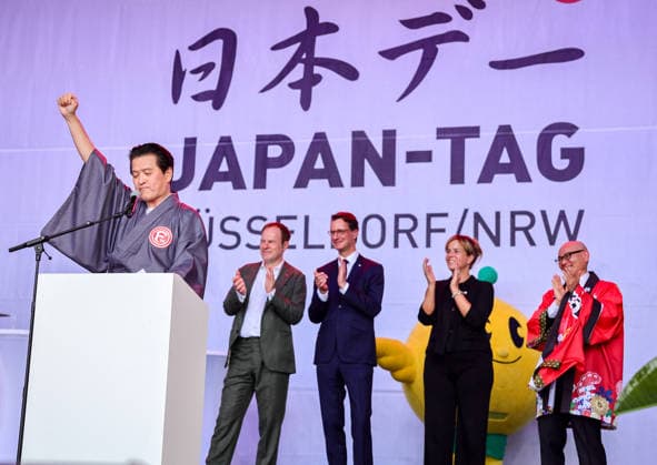 Japan-Tag 2026 in Düsseldorf, einzigartiges Kulturfest in der Landeshauptstadt von NRW - Takao Hariya, Präsident des japanischen Clubs in Düsslddorf bei seienr Begrüssungsrede - im Hitergrund stehen NRW Ministerpräsident Hendrik Wüst, NRW Ministerin für Wirtschaft und Kultur Mona Neubaur und der japanische Generalkonsul für Düsseldorf Yoshitaka Tsunoda überraschte die Zuschauer als bekennender Fan von Fortuna Düsseldorf - im Hintergrund Applaus von Düsseldorfs OB Dr. Stephan Keller, NRW Ministerpräsident Hendrik Wüst, NWR Wirtschafts & Kultur Ministerin Mona Neubaur und dem japanischen Generalkonsul für Düsseldorf Yoshotaka Tsunoda auf der Bühne... Düsseldorf Burgplatz NRW Deutschland *** Japan Day 2026 in Düsseldorf,