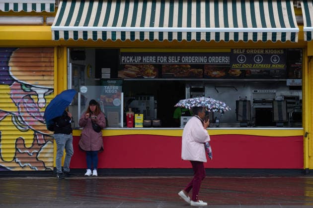 May 23, 2026, New York, New York, USA: People carry umbrellas on the boardwalk and take shelter under the awning of a fast food counter on the day of the official opening of the 2026 Summer beach season in Coney Island, Brooklyn. New York USA  - ZUMAl171 20260523_znp_l171_002 Copyright: xEdnaxLeshowitzx
