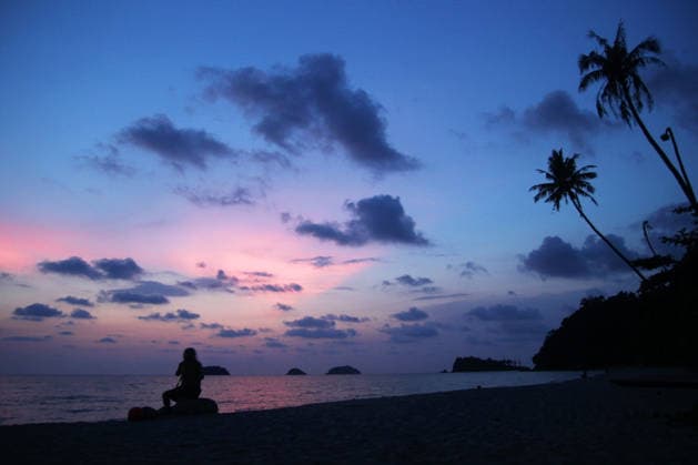 Ein unbekannter Mann sitzt bei Sonnenuntergang auf den Steinen an einem Sandstrand in Meeresnähe. Koh Chang, Thailand. Unrecognizable man is sitting on the stones at the sunset on a sandy beach near to sea. Koh Chang, Thailand. (License=RF) Copyright: xZoonar.com NadezhdaxZaitsevax 25063992