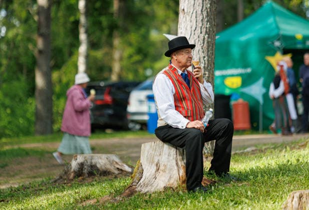 Polva, 24.05.2026. The 32nd South Estonian Memme-Taadi Festival at the Intsikurmu song festival grounds in Polva. The event brought together nearly 1,000 performers from senior singing groups, dance collectives, and folk musicians across four southern counties. Photo Arvo Meeks, Louna-Eesti Postimees Polva Polvamaa Estonia 2MA25MAI2026A050  Copyright: xArvoxMeeksx Elderly man in traditional costume, eating ice-cream