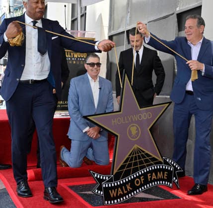 Comedy, actor, radio personality and television host Adam Corolla (kneeling) reacts during an unveiling ceremony honoring him with the 2,846th star on the Hollywood Walk of Fame in Los Angeles on Wednesday, May 27, 2026.  LAP2026052701 JIMxRUYMEN
