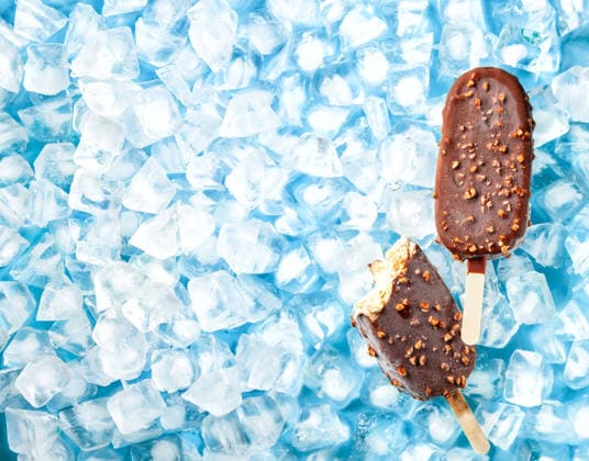 Crème-Brûlée-Eis am Stiel. Cream brulee ice cream popsicles covered milk chocolate and nuts on ice. Top view. (License=RF) Copyright: xZoonar.com SvetlanaxKolpakovax 25142466