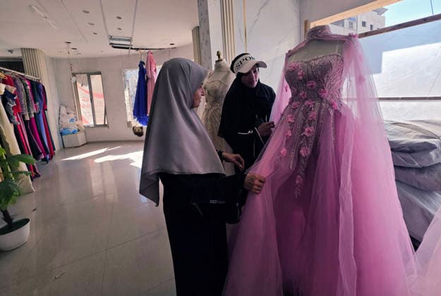 Customers browse wedding attire in Khan Younis despite wartime hardships Customers browse wedding dresses and suits inside a bridal shop in Khan Younis in the southern Gaza Strip on June 1, 2026, as Palestinians continue to uphold marriage traditions despite the ongoing war, widespread destruction, and difficult economic and humanitarian conditions. Shop owners say demand for wedding supplies remains present, though at a lower pace, as many families turn to less costly options amid declining incomes, rising prices, and shortages of goods linked to Israeli restrictions at border crossings. Photo by Tariq Mohammad APA Images Khan Yunis Gaza Strip Palestinian Territory 010626_Khan_Yunis_TM_00(27) Copyright: xapaimagesxTariqxMohammad xapaimagesx