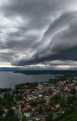 Ein Frühsommertag in Tutzing (Landkreis Starnberg). Hier der Blick über die Ortschaft und den Starnberger See mit der Alpenkette am Horizont, wo gerade ein Unwetter aufzieht, drüberzieht, eine Wolkenwand, Gewitterwalze, Wolkenrolle, Gewitterfront, Gewitterrolle, Unwetterfront, dunkle Wolken, Wetterbild *** An early summer day in Tutzing, Starnberg district Here the view over the village and Lake Starnberg with the Alps on the horizon, where a thunderstorm is just coming up, a wall of clouds, thunderstorm roll, cloud roll, thunderstorm front, thunderstorm roll, thunderstorm front, dark clouds, weather picture