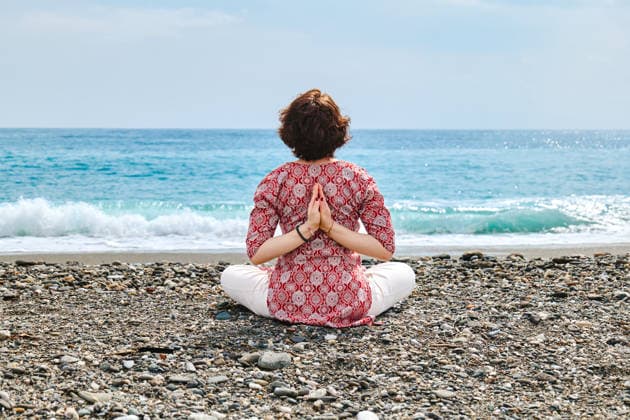 Person practicing yoga on a pebble beach by the Mediterranean sea model released, Symbolfoto, CATF00969
