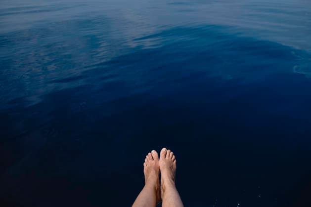 Point of view of bare feet dangling over calm blue sea water model released, Symbolfoto, GMLF01653