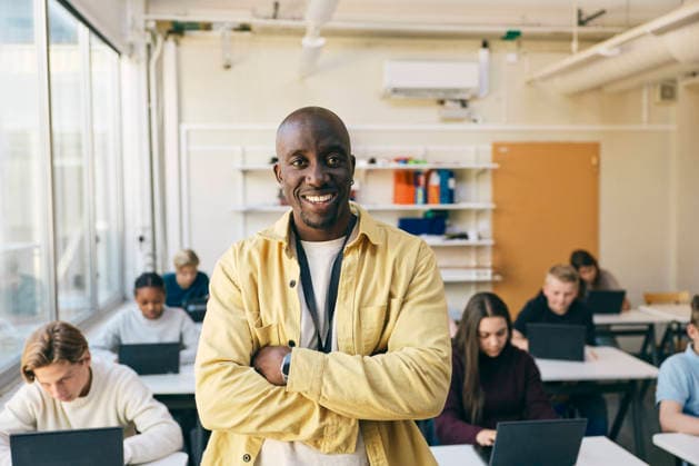 Portrait of smiling teacher standing with arms crossed in classroom at junior high school Sweden, Stockholm, model released, property released Copyright: xMaskotx , MA125461 MA125461