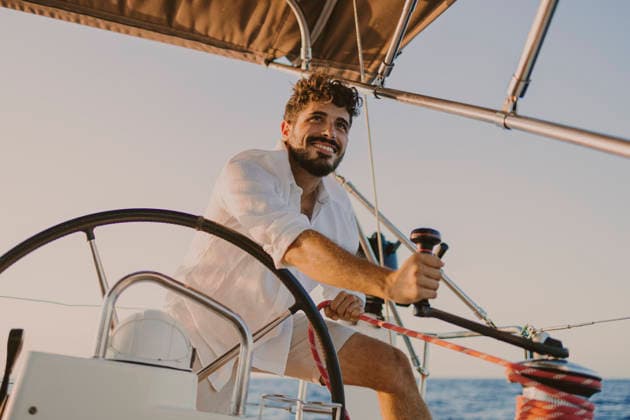 Sailor steering a sailboat on the ocean during summer vacation model released, Symbolfoto property released, GMLF01887