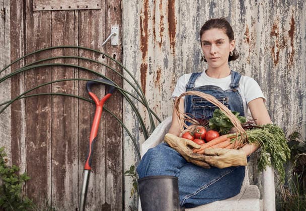 Woman sitting with basket of fresh produce on allotment in London model released, Symbolfoto property released, PWF01552