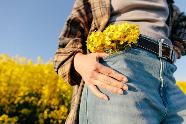 Hand on denim pocket with yellow flowers in spring countryside model released, Symbolfoto, SIF01540