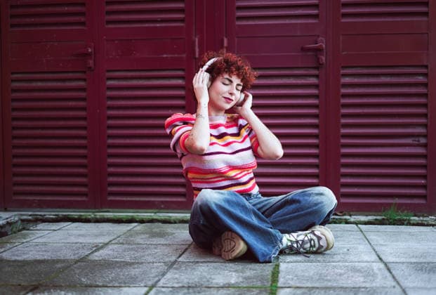 Redhead sitting outdoors listening to music model released, Symbolfoto, SVCF00702