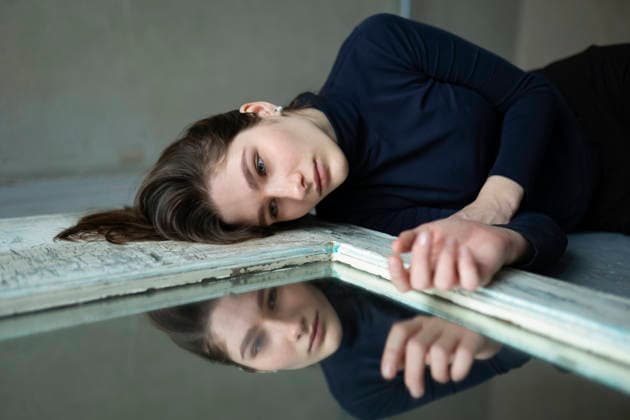 Model lying on floor looking at mirror reflection in sadness model released, Symbolfoto, VCF01582