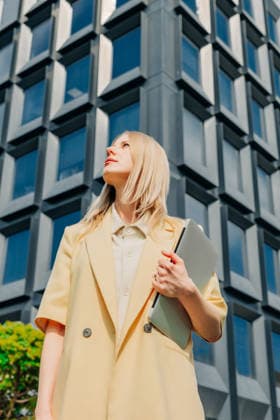 Businesswoman holding laptop looking up outside office building model released, Symbolfoto, VSNF04839