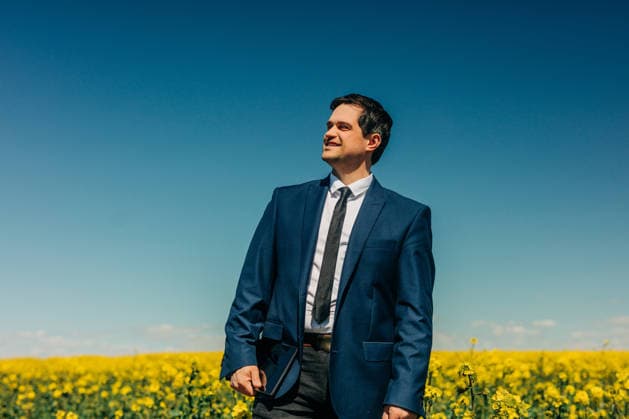 Smiling businessman with tablet standing in yellow rapeseed field model released, Symbolfoto, VSNF04877