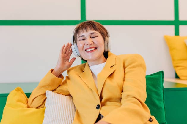 Smiling businesswoman listening to music in modern workspace model released, Symbolfoto property released, VSNF04900