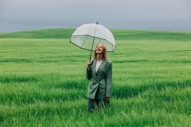 Smiling woman in green suit holding umbrella in wheat field model released, Symbolfoto, VSNF04974