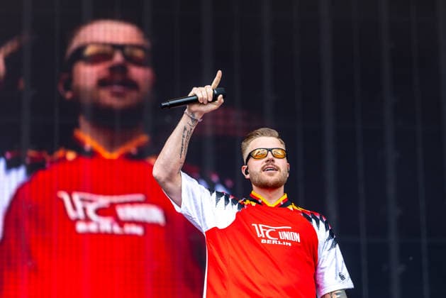 Musikfestival Rock im Park 2026 - FINCH, Nürnberg, 06.06.2026 Rapper Finch mit Mikrofon und erhobenem Zeigefinger auf der Buehne. Der Kuenstler traegt ein Trikot von 1. FC Union Berlin und eine Sonnenbrille mit orangefarbenen Glaesern. Nürnberg Bayern Deutschland *** Music festival Rock im Park 2026 FINCH, Nuremberg, 06 06 2026 Rapper Finch with microphone and raised index finger on stage The artist wears a jersey of 1 FC Union Berlin and sunglasses with orange-colored glasses Nuremberg Bavaria Germany 20260606-1V9A0142-M4000