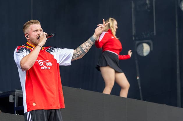 Musikfestival Rock im Park 2026 - FINCH, Nürnberg, 06.06.2026 Rapper Finch performt mit Mikrofon auf der Bühne, im Hintergrund tanzt eine Tänzerin. Er trägt ein rotes Trikot des 1. FC Union Berlin. Nürnberg Bayern Deutschland *** Music festival Rock im Park 2026 FINCH, Nuremberg, 06 06 2026 Rapper Finch performs with microphone on stage, a dancer dances in the background He wears a red jersey of 1 FC Union Berlin Nuremberg Bayern Germany 20260606-1V9A0231-M4000