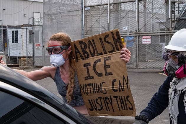 June 6, 2026, Newark, New Jersey, USA: A protester holding a sign reading Ã¢â‚¬oeAbolish ICE, nothing can justify thisÃ¢â‚¬oe stands in front of an ICE vehicle outside of the Delaney Hall immigration detention center in Newark. Newark USA - ZUMAh196 20260606_znp_h196_003 Copyright: xTomxHudsonx