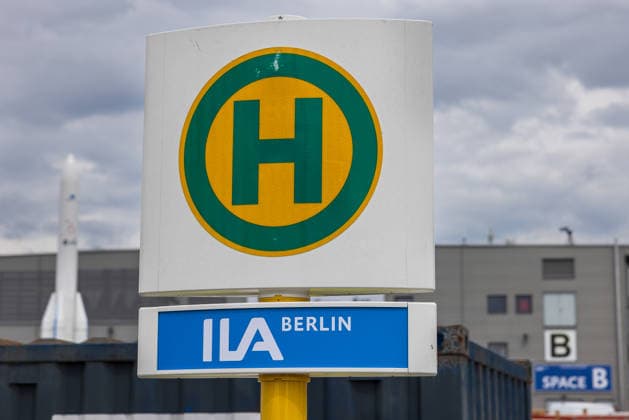 Presserundgang auf der ILA Berlin 2026, Berlin, 09.06.2026 Bushaltestelle mit dem Haltestellenschild ILA Berlin auf dem Messegelaende. Im Hintergrund ist ein Raketenmodell sowie ein Hallengebaeude mit dem Schriftzug Space B zu sehen. *** Press tour at the ILA Berlin 2026, Berlin, 09 06 2026 Bus stop with the ILA Berlin stop sign on the exhibition grounds In the background you can see a rocket model and a hall building with the lettering Space B 20260609-286A9180-M4000