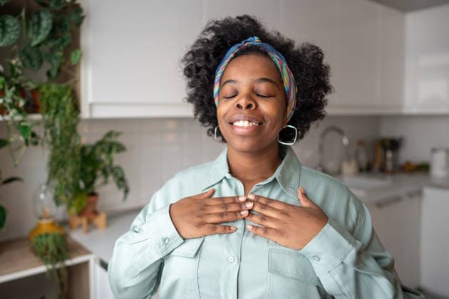 Selbstfürsorge, Glaube, emotionale Erfüllung einer lächelnden schwarzen Frau, die zu Hause mit den Händen auf der Brust steht Happy African American female smiling, hands placed on chest with faith. Spiritual connection, gratitude practices. Inner strength, emotional fulfillment of black woman feeling joy by simple pleasure (License=RF) ,model released, Symbolfoto Copyright: xZoonar.com IrinaxRomanovax 25169530 ,model released, Symbolfoto ,property released